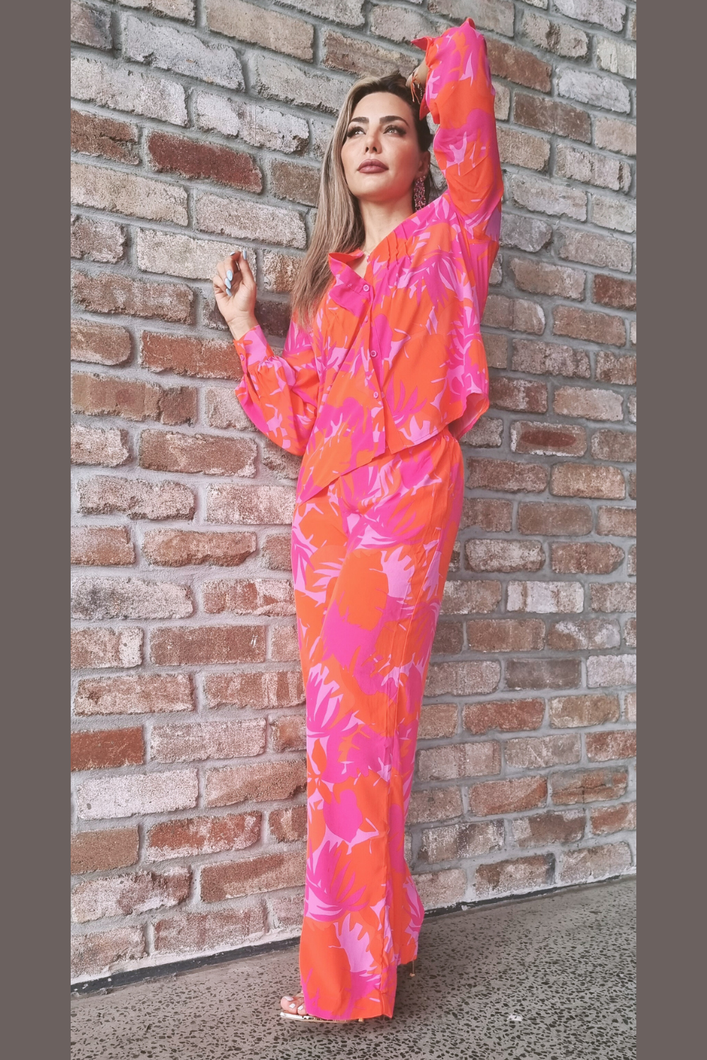 Woman wearing a pink and red palm print blouse and pants set