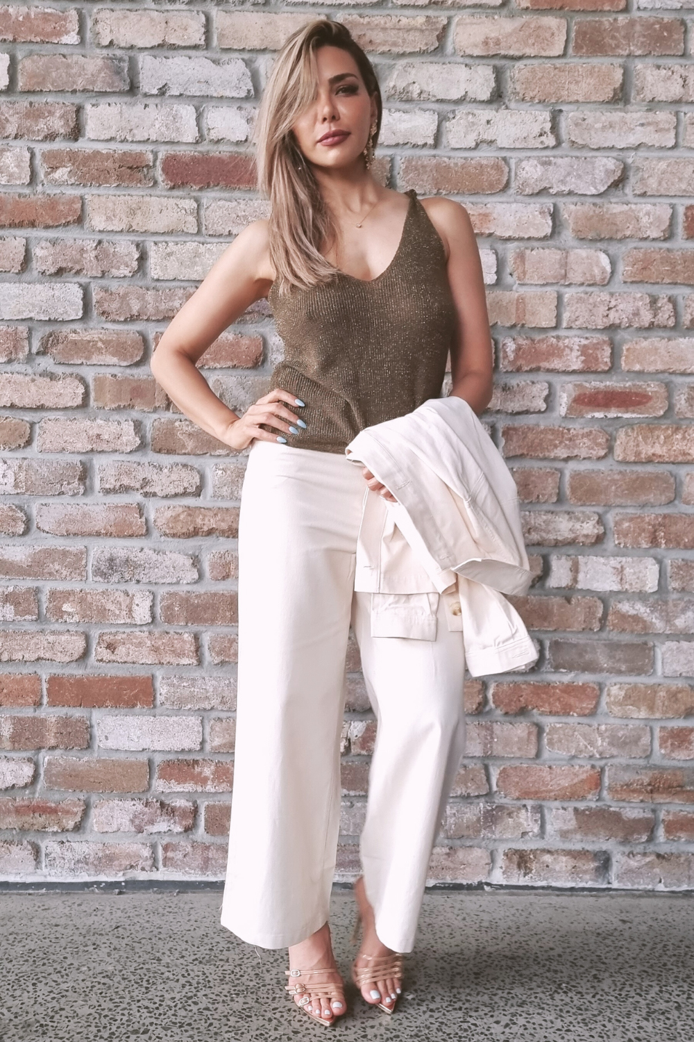 Woman standing against a wall wearing cream coloured wide leg pants