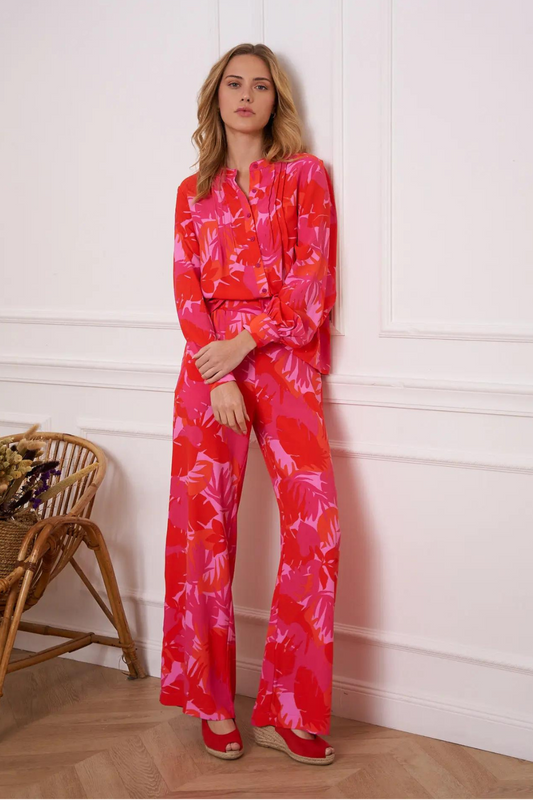 Woman wearing a pink and red palm print blouse and pants set