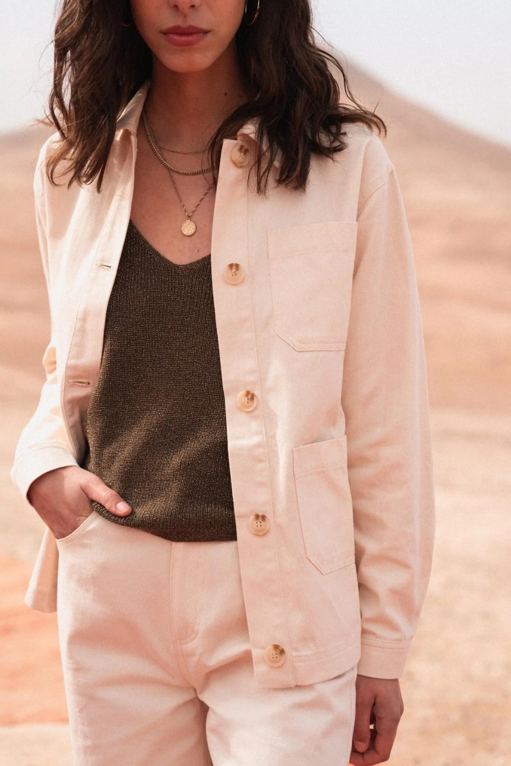 Model wearing an ecru jacket and khaki knit tank top