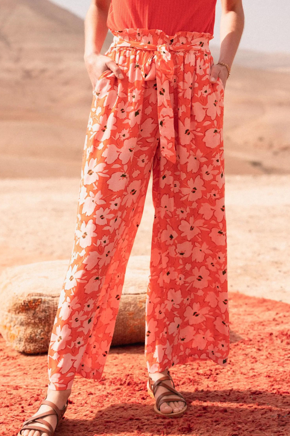 Woman wearing coral red tank top and flower print wide leg pants 