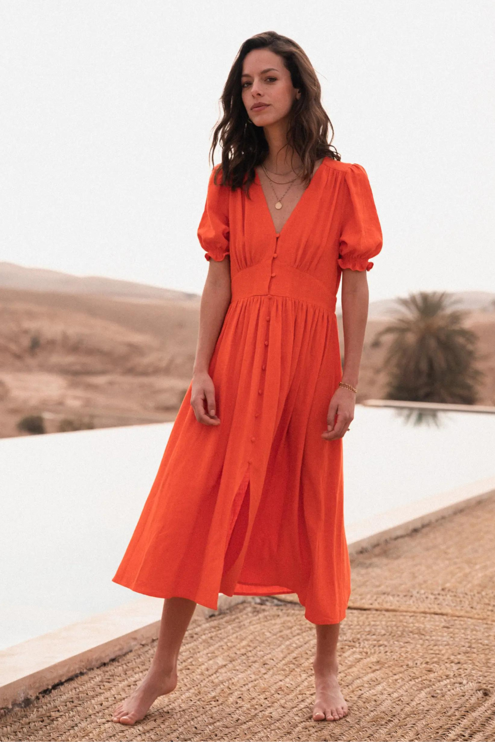 Model wearing an orange midi dress with V-neckline and puff sleeve