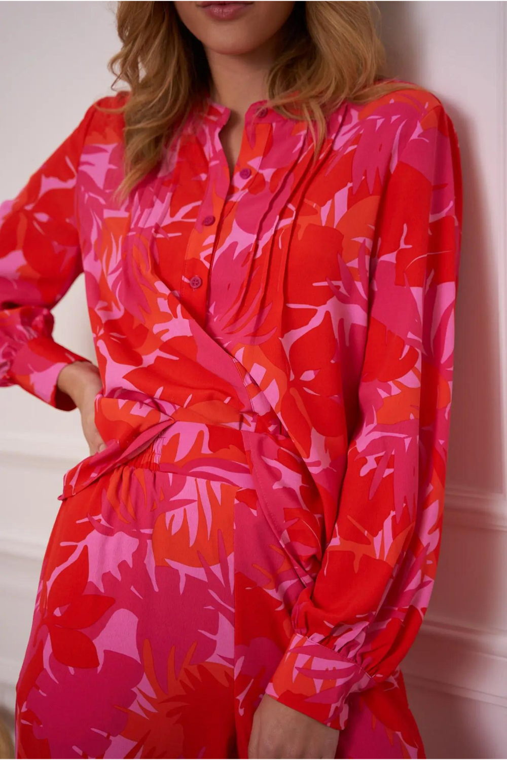 Woman wearing a pink and red palm print blouse and pants set