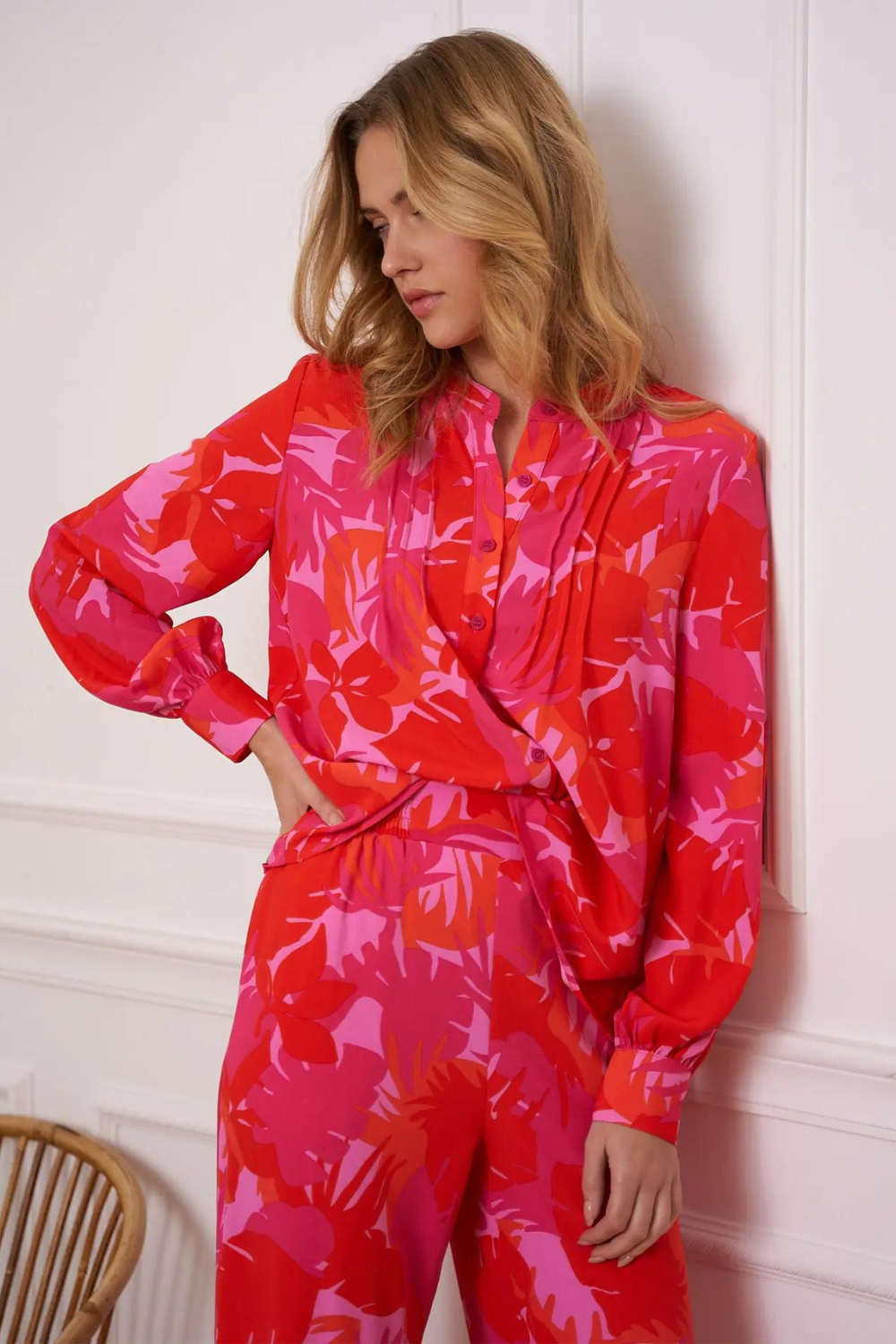 Woman wearing a pink and red palm print blouse and pants set