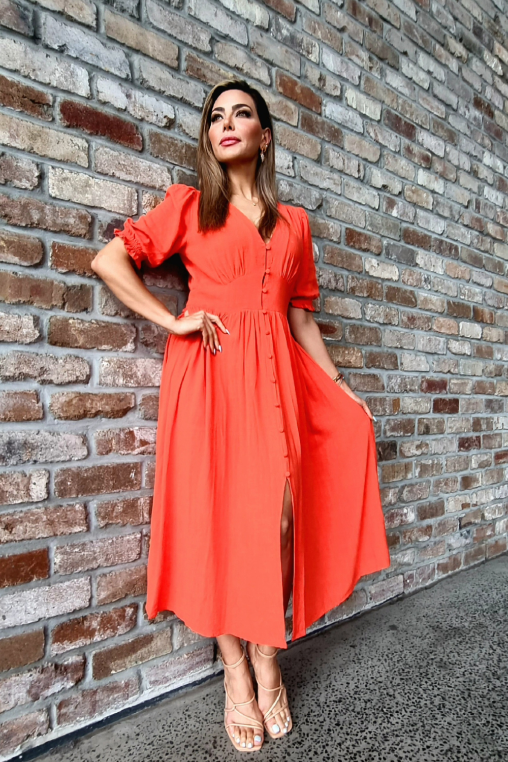 Model wearing an orange midi dress with V-neckline and puff sleeve