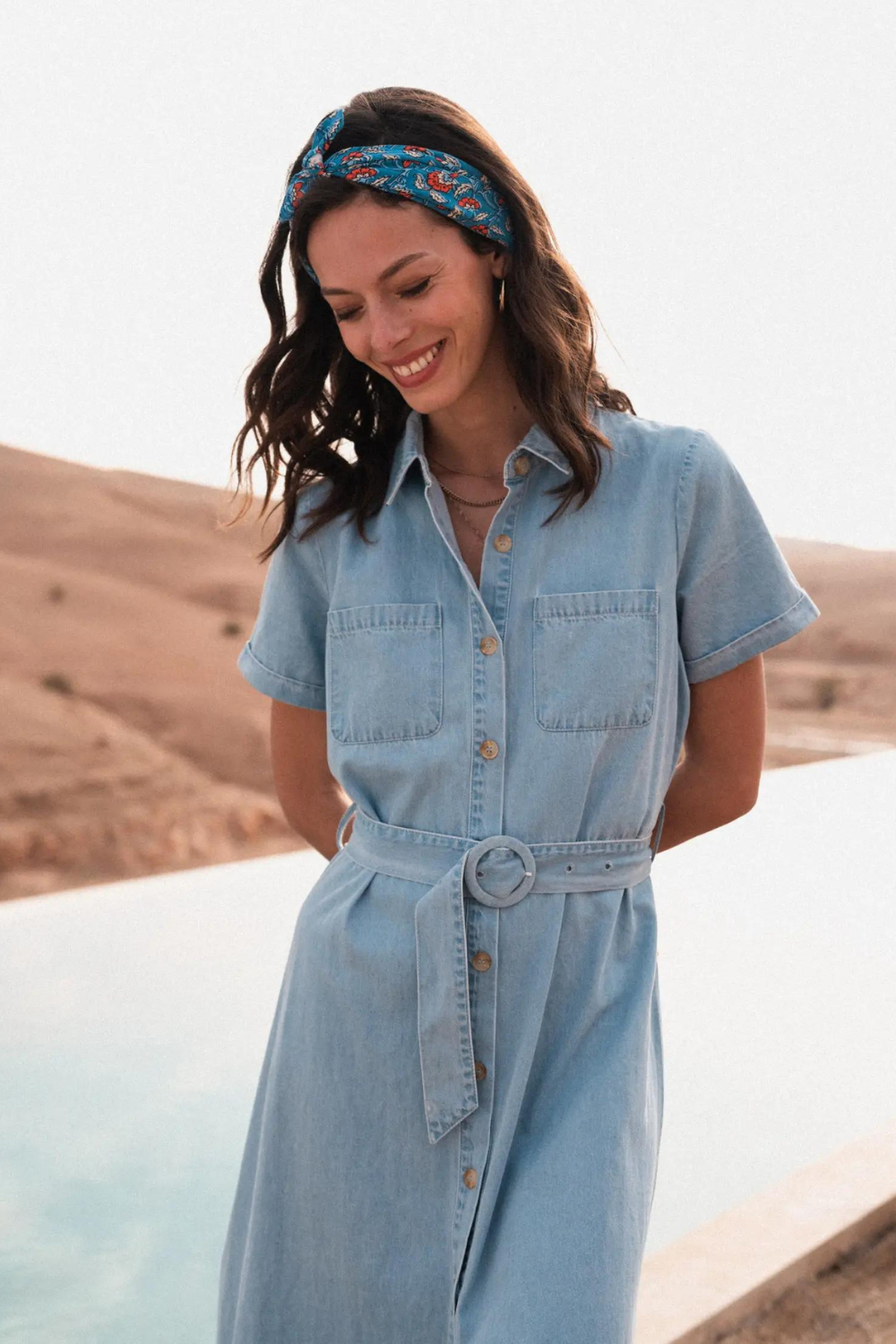 Woman modeling a blue head scarf wearing a denim dress