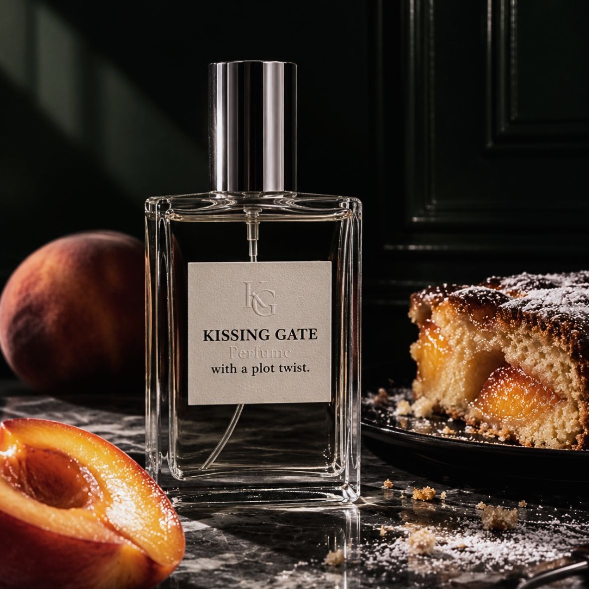 A clear rectangular perfume bottle labeled 'Kissing Gate For one with a plot twist.' stands on a dark marble surface, flanked by fresh peaches and a slice of peach cake.